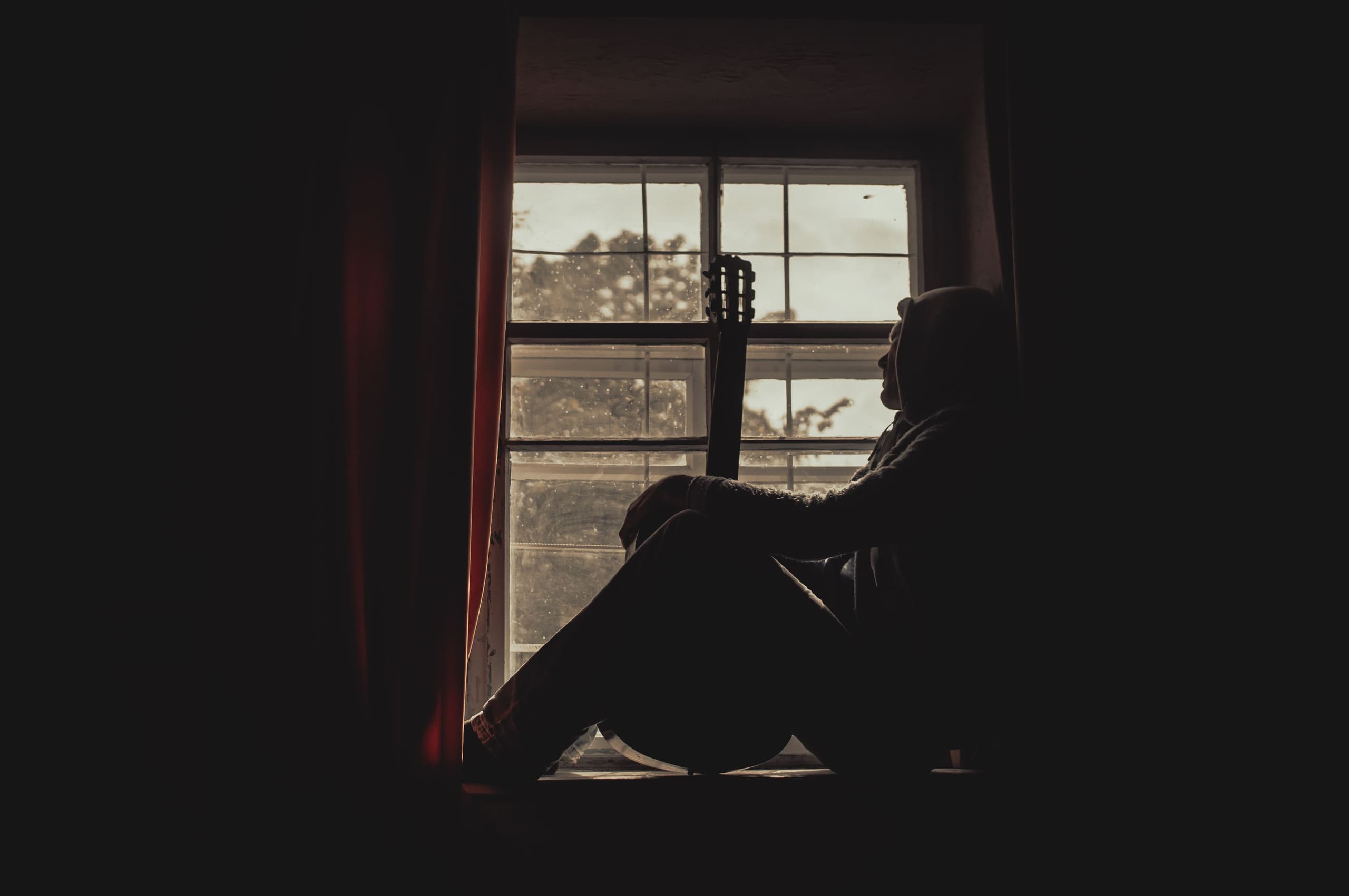 A man sitting by a window, lost somewhere else
