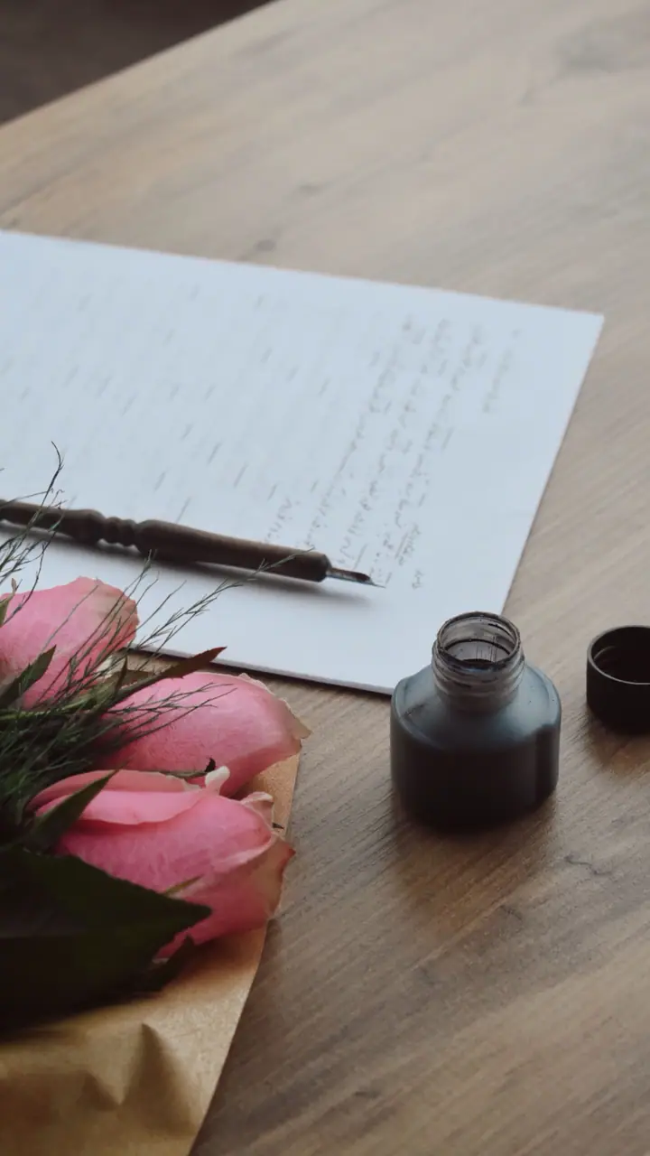 A letter, an ink bottle and roses left on a desk